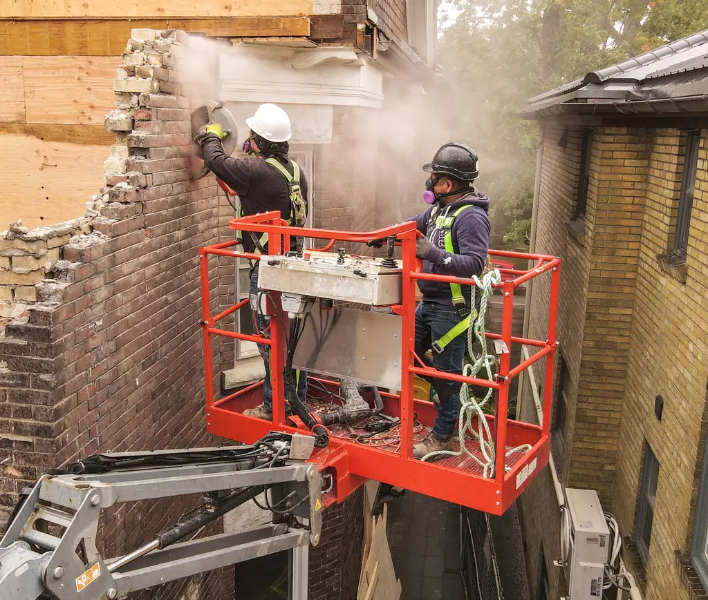 MAGCOR crew carrying out manual demolition on a brick wall from a platform