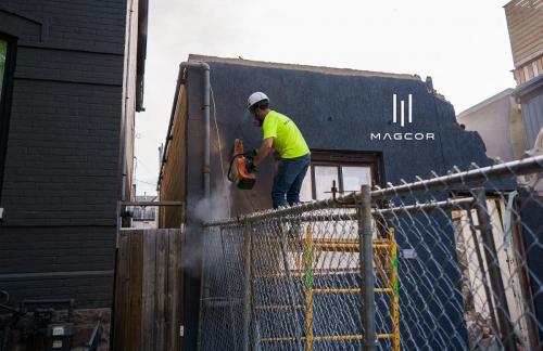 Demolition man sawing through portion of exterior wall